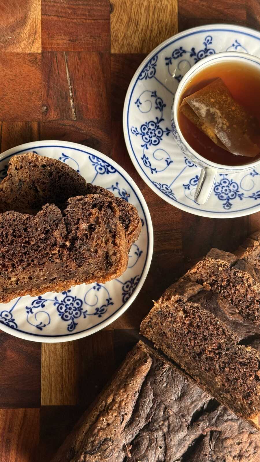 Saftigt bananbröd med smält choklad på tallrik intill en kopp med te
